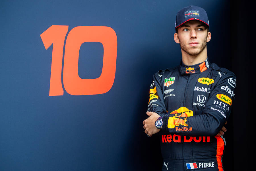 Pierre Gasly Striking A Pose Beside His Race Car Wallpaper