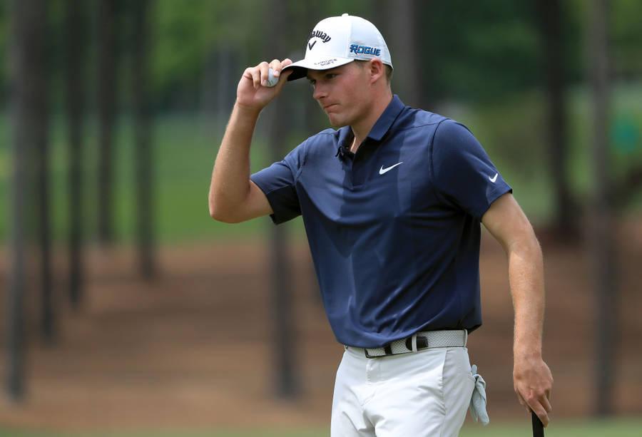 Pro Golfer Aaron Wise Holding His Cap In A Contemplative Moment Wallpaper