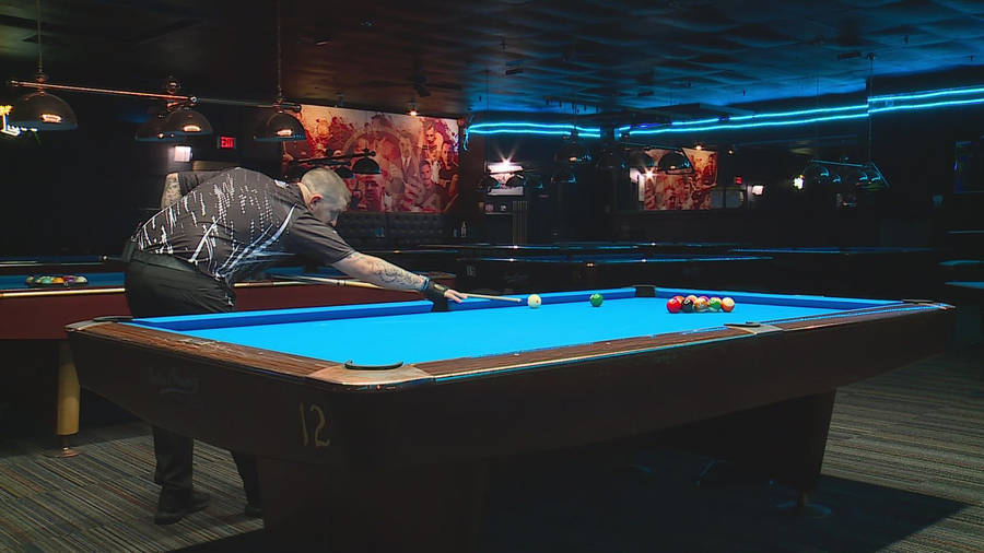 Professional Billiards Player In Action On A Vibrant Blue Pool Table. Wallpaper