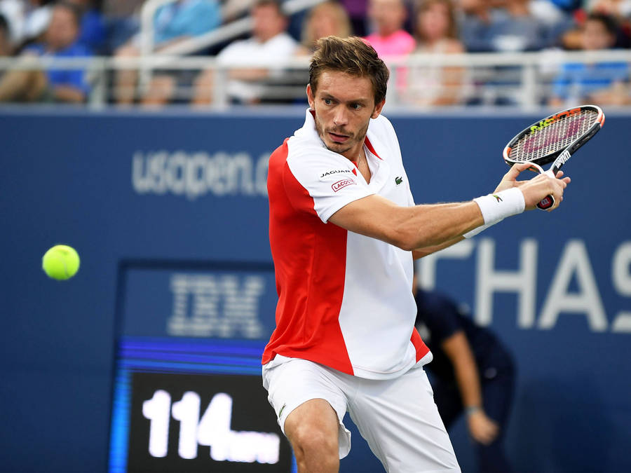 Professional Tennis Player Nicolas Mahut Intensely Focusing On The Ball During A Match. Wallpaper