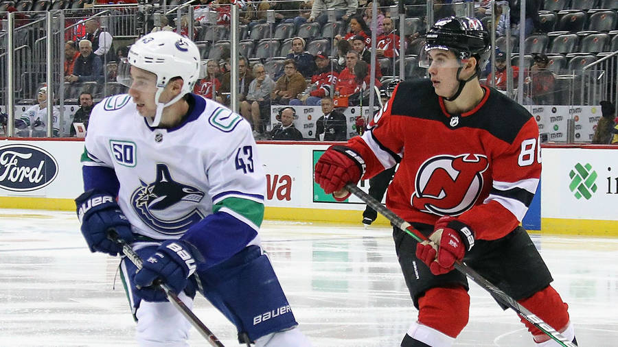 Quinn Hughes Skating Playing Against Brother Jack Hughes During Game Wallpaper