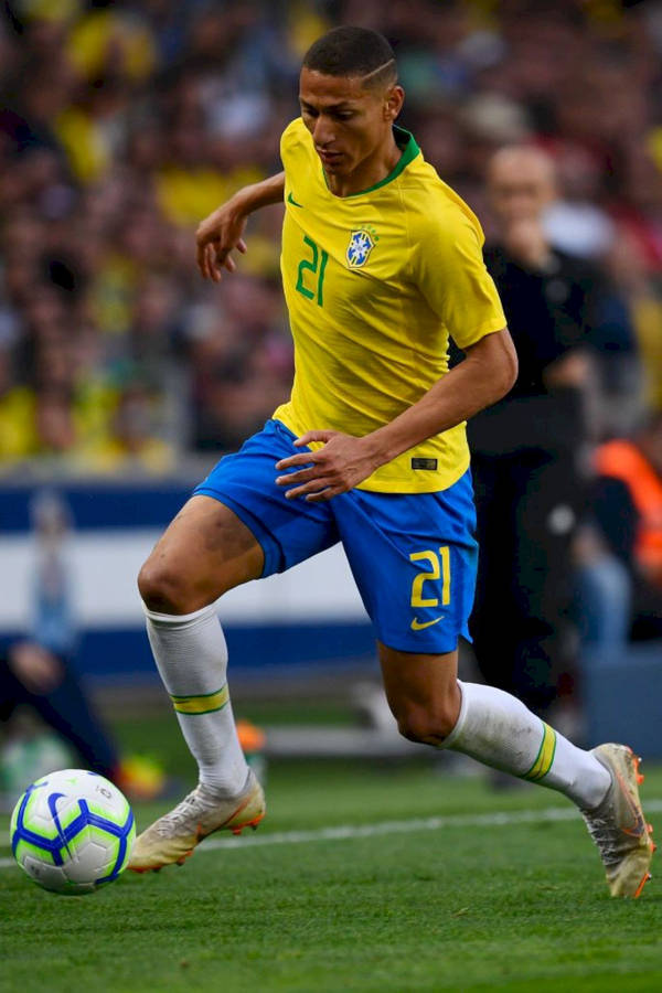 Richarlison De Andrade Skillfully Dribbling A Football During A Match Wallpaper