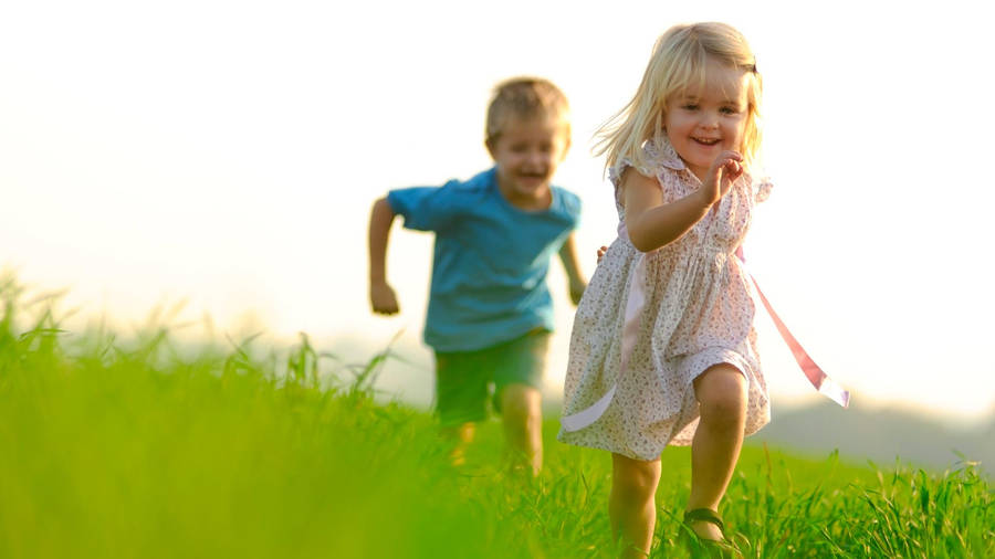 Running Children On A Grass Field Wallpaper