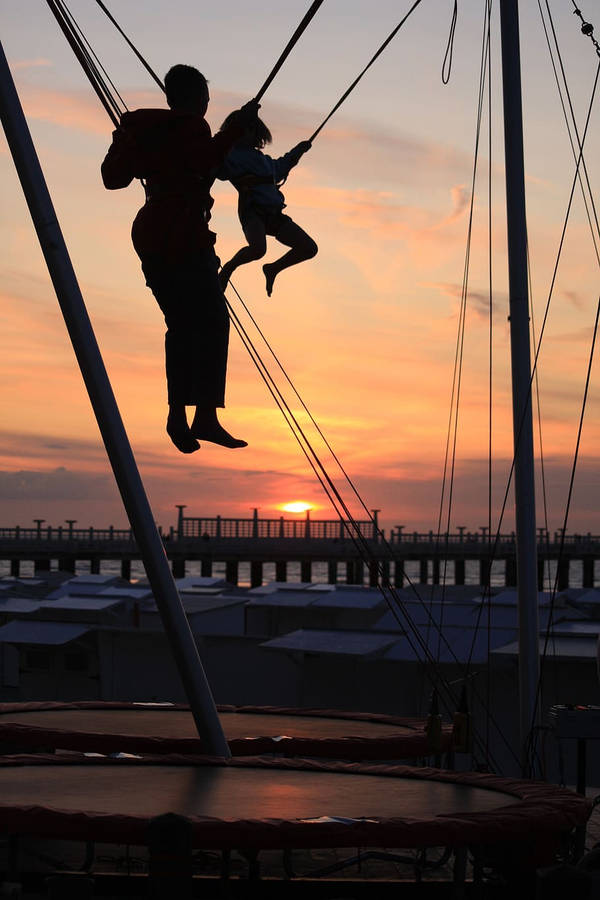 Silhouetted Father And Son Jumping From Trampoline Wallpaper