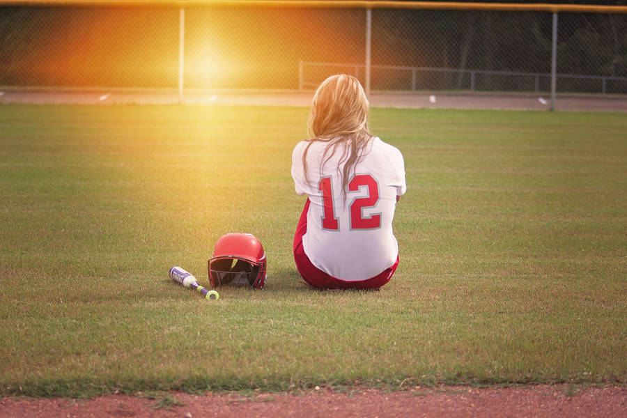 Softball Player Seated On Playing Field Wallpaper
