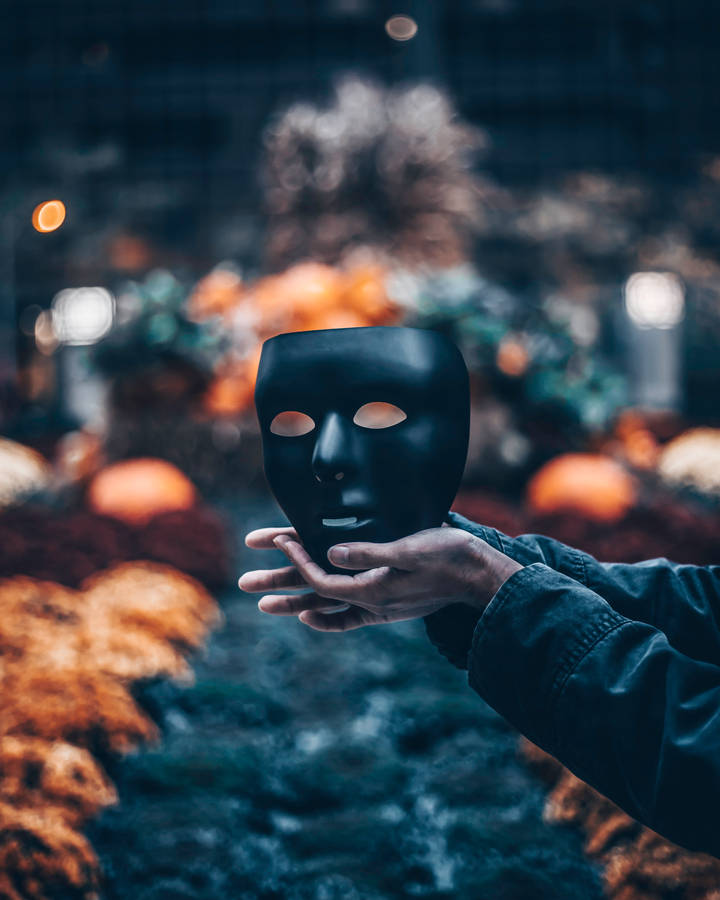 Spooky Black Mask In Hand Wallpaper