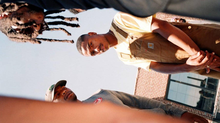 Steve Lacy Wearing Brown Overalls Wallpaper