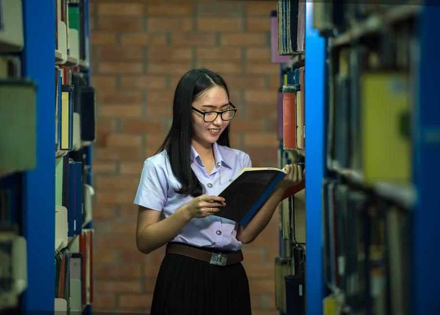 Student Reading Reference Book In Aisle Wallpaper