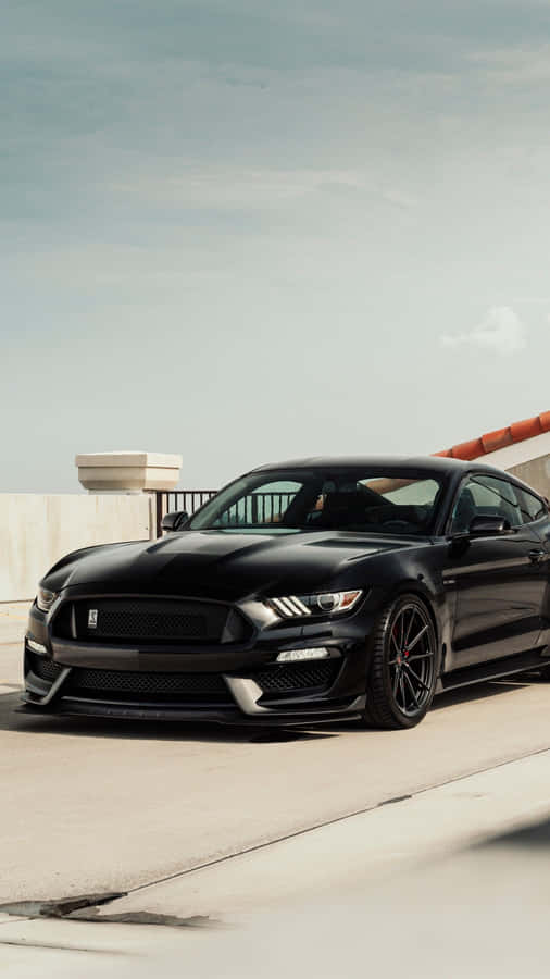 The Black Mustang Gt Is Parked On The Side Of The Road Wallpaper