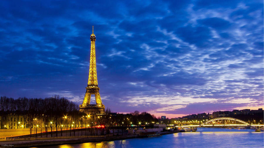 The Iconic Paris Eiffel Tower Overlooking The Seine River Wallpaper