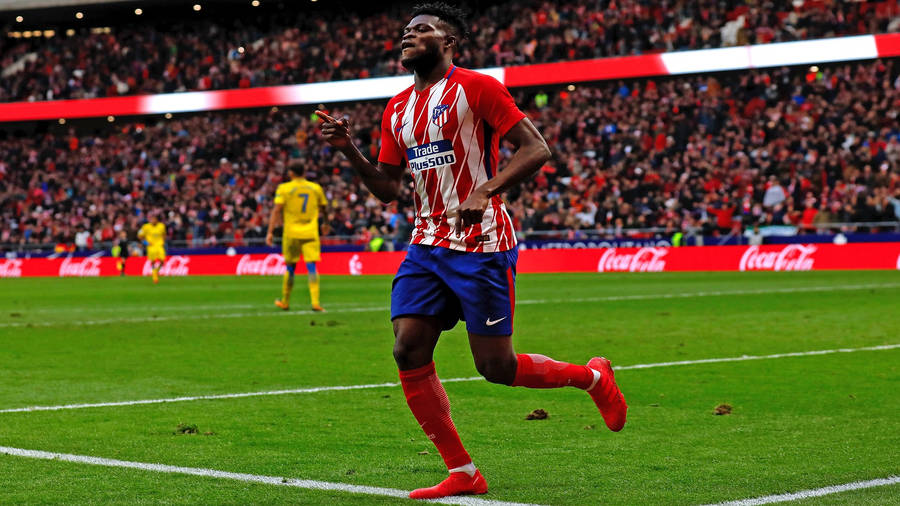 Thomas Partey Running Across A Green Field Wallpaper