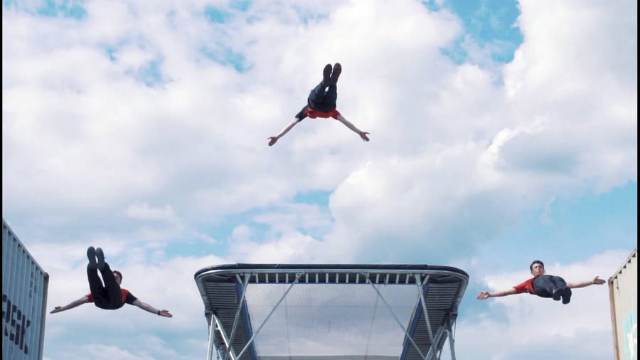 Three Guys High Jumping From A Trampoline Wallpaper