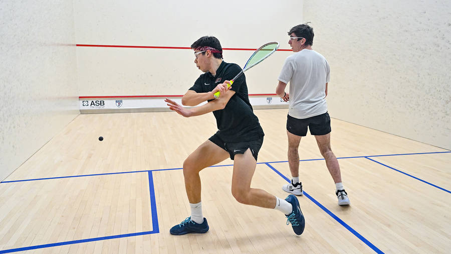 Two Men Looking At Squash Ball Wallpaper