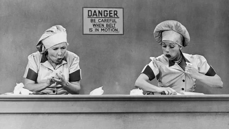 Two Women In Hats Are Sitting At A Table Wallpaper