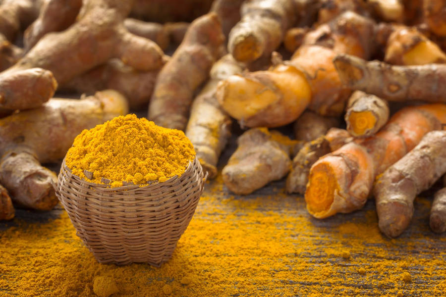 Vibrant Basket Of Turmeric Powder And Whole Turmeric Wallpaper