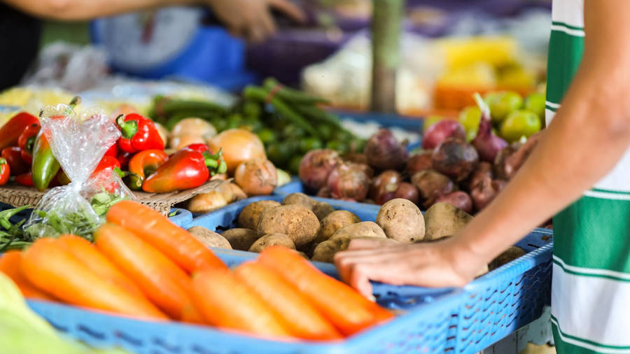 Vibrant Display Of Fresh Carrots At A Public Market Wallpaper