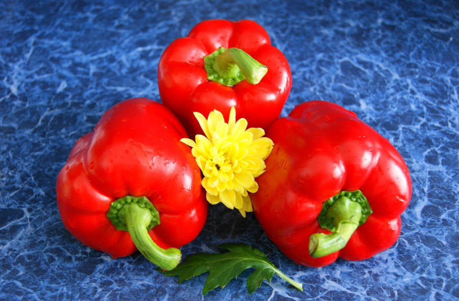 Vibrant Red Bell Pepper Besieged By Yellow Dahlias Wallpaper