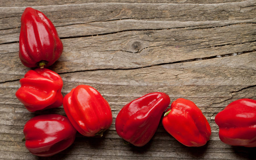 Vibrant Red Chili Peppers On Rustic Wooden Surface Wallpaper