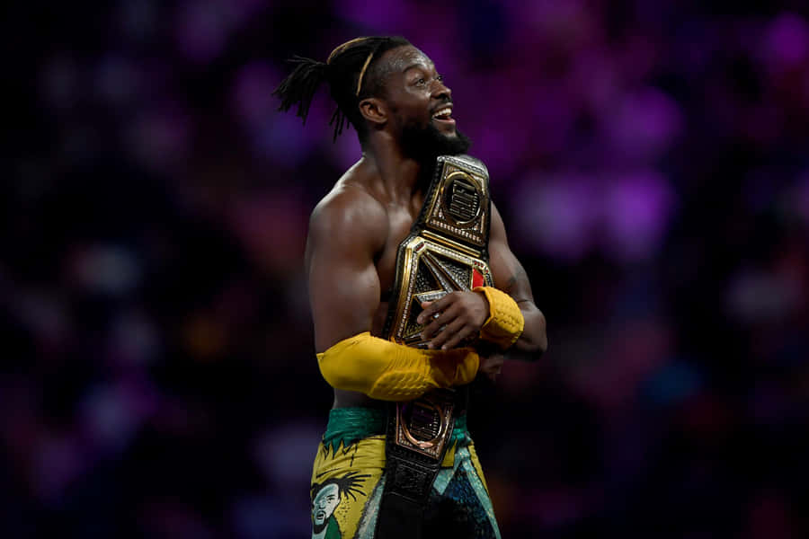 Victorious Kofi Kingston Hugging His Wwe Belt Wallpaper