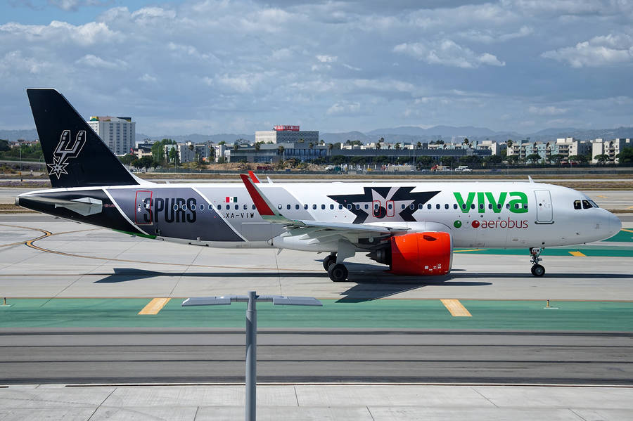 Viva Aerobus Side View With City Background Wallpaper