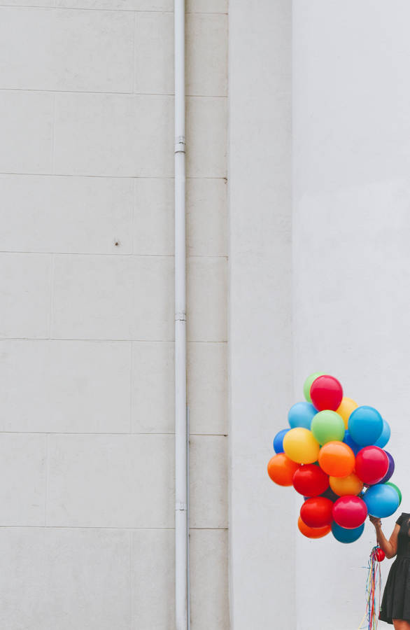 Woman Holding Bunch Of Colorful Balloons Wallpaper
