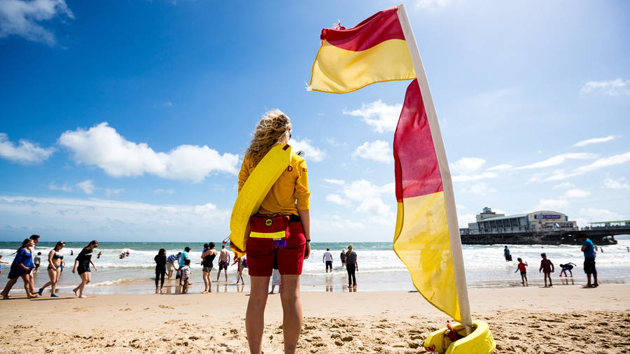 Woman Lifeguard Standing Beside Flag Wallpaper