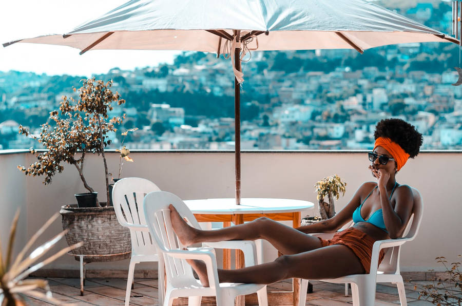 Woman Relaxing Under A Patio Umbrella Wallpaper