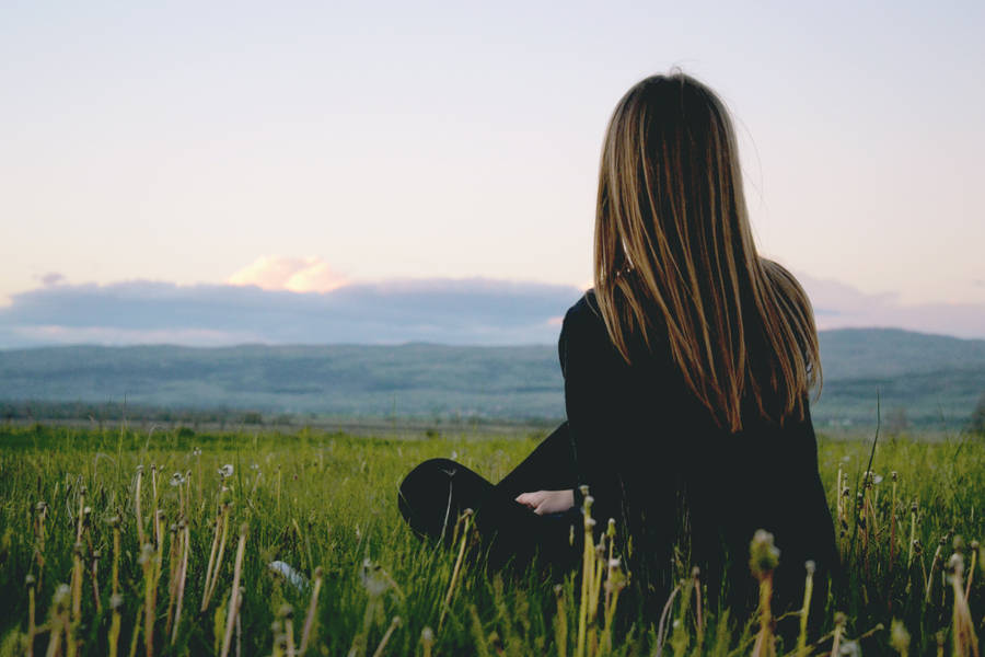 Woman Sitting Alone On Grassy Plain Wallpaper