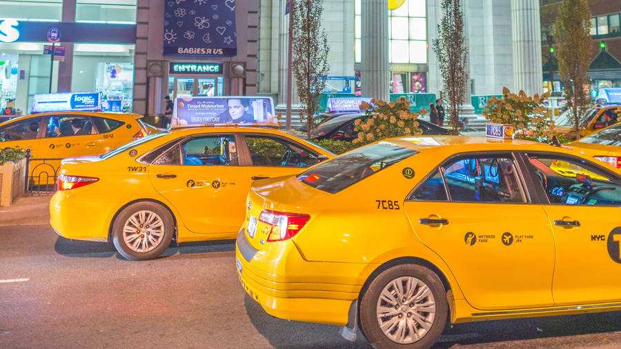 Yellow Taxi Cab In Front Of Mall Wallpaper