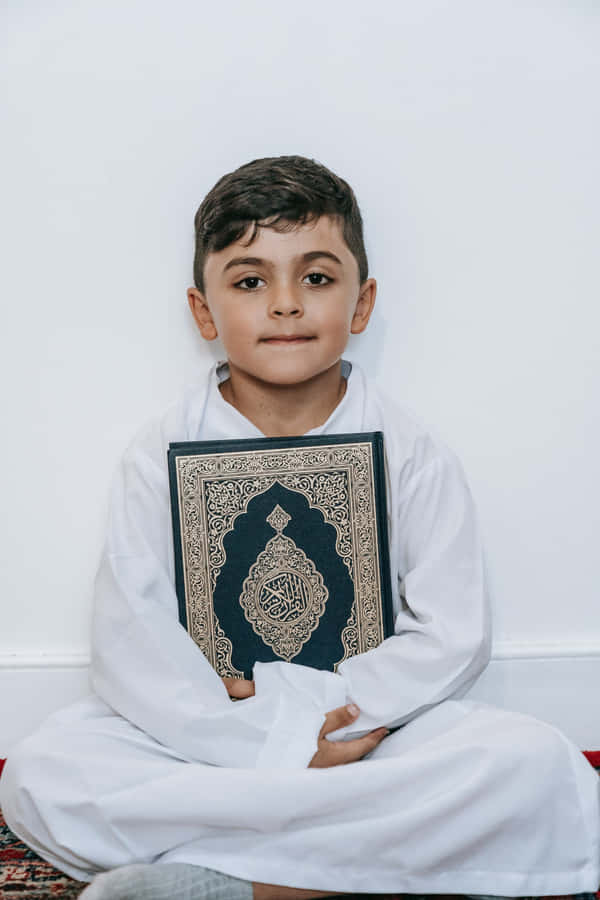 Young Muslim Boy Holding Quran Book Wallpaper