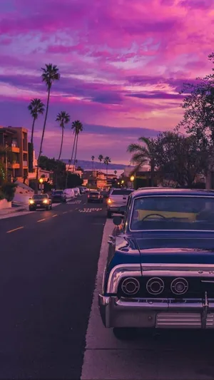 A Classic Car Parked On The Street At Sunset Wallpaper