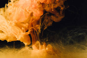A Cloud Of Orange Smoke Against A Black Background Wallpaper