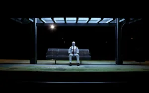 A Clown Waiting Alone At A Bus Stop. Wallpaper