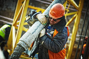 A Construction Worker Guiding A Hose On Site Wallpaper