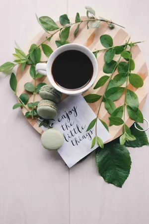 A Cup Of Coffee With Macarons And Greenery On A Wooden Plate Wallpaper