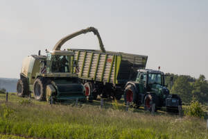 A Diligent Farmer Operating A Thresher On A Tractor In The Field. Wallpaper