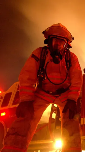 A Firefighter Standing In Front Of A Fire Truck Wallpaper