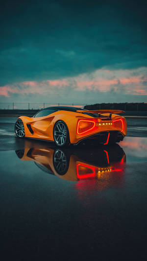 A Futuristic Orange Car Sitting On A Wet Surface Wallpaper