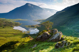 A Green Grassy Hillside With A Lake Wallpaper