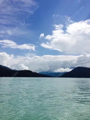 A Lake With Mountains And Clouds In The Background Wallpaper