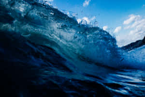 A Lone Surfer Overwhelmed By Powerful Waves Wallpaper