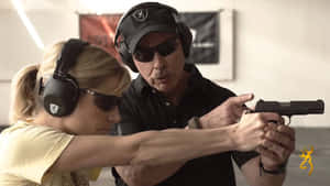 A Man And Woman Are Holding A Gun Wallpaper