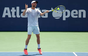 A Man Is Playing Tennis On A Tennis Court Wallpaper