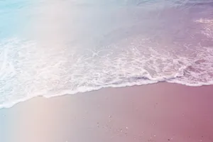 A Man Is Standing On A Beach With A Surfboard Wallpaper