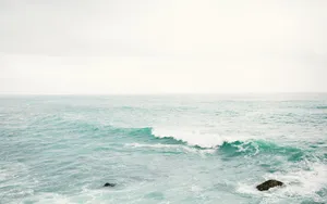 A Man Is Standing On A Rock In The Ocean Wallpaper