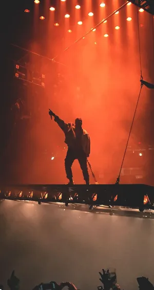 A Man Is Standing On A Stage With A Light On Wallpaper