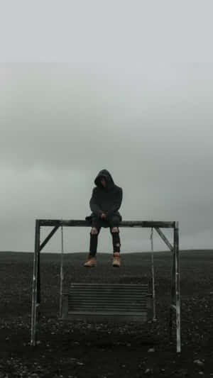 A Man Sitting On A Bench In A Field Wallpaper