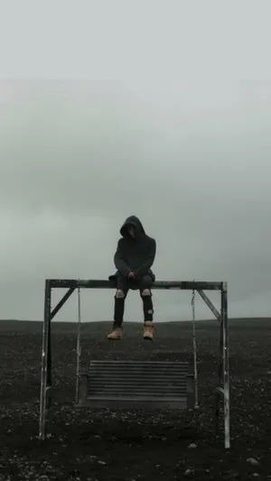 A Man Sitting On A Bench In A Field Wallpaper