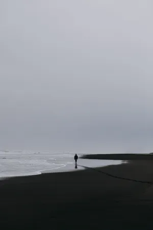 A Man Walking Alone On The Beach With His Phone Wallpaper