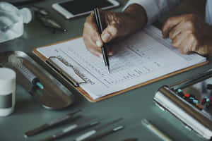A Man Writing On A Clipboard With Medical Supplies Wallpaper